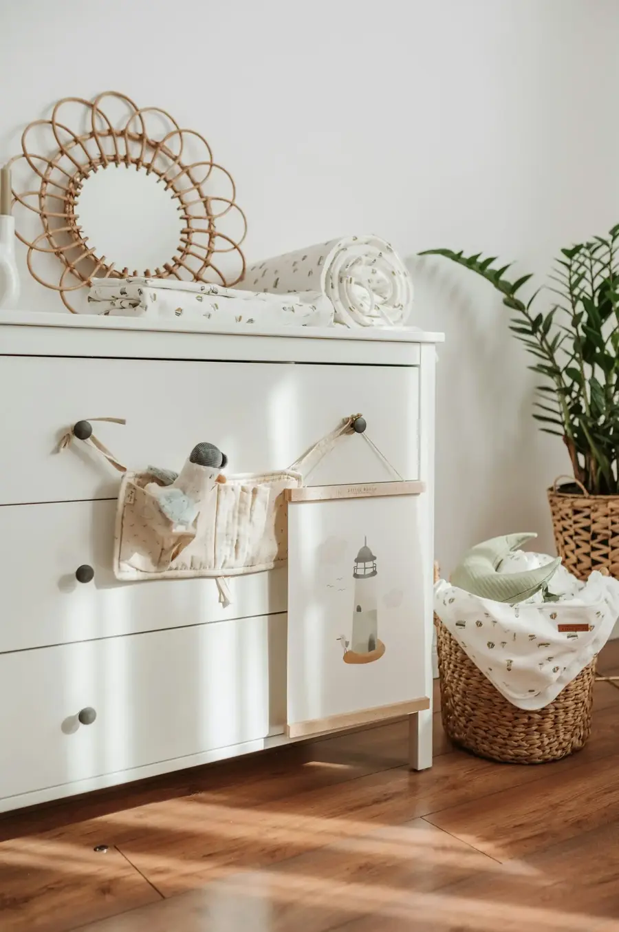 White dresser with a basket and baby items in an organized room