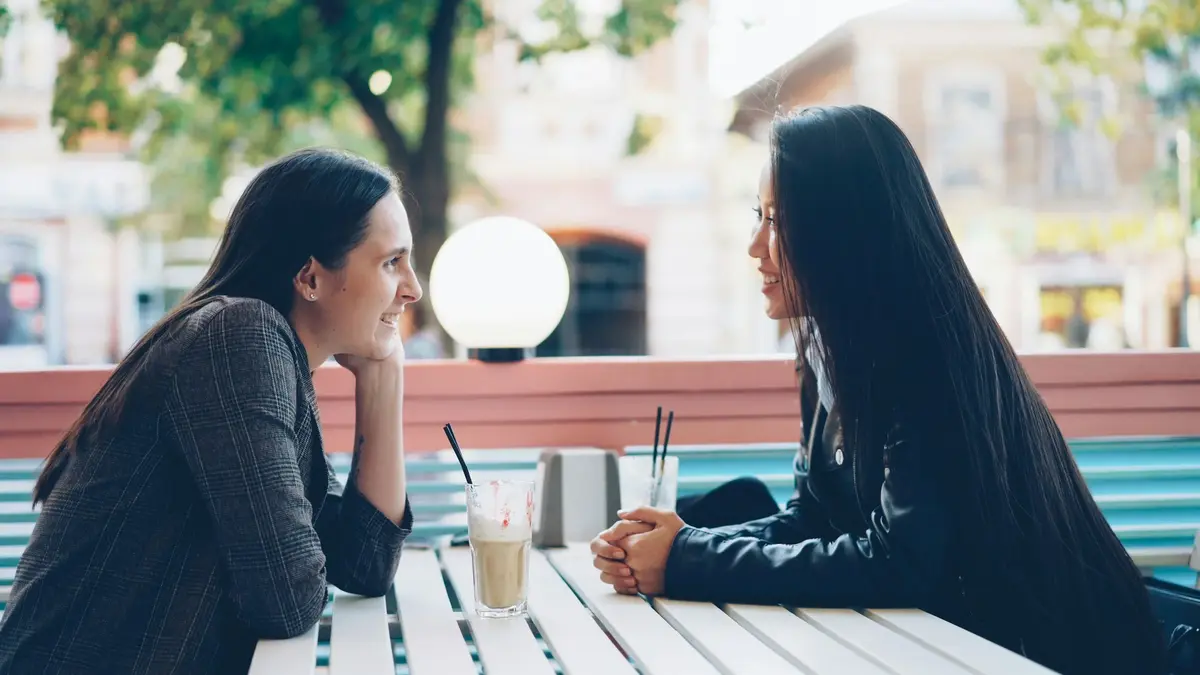 Two women talking across a cafe table