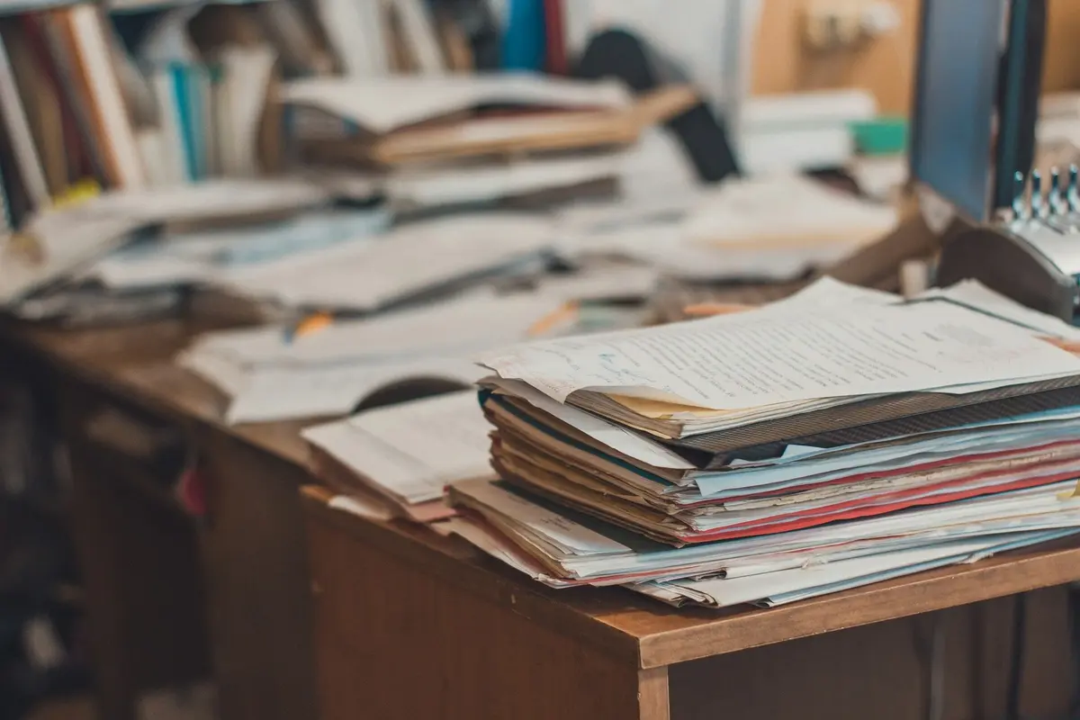 Stacks of papers and notebooks on a busy desk