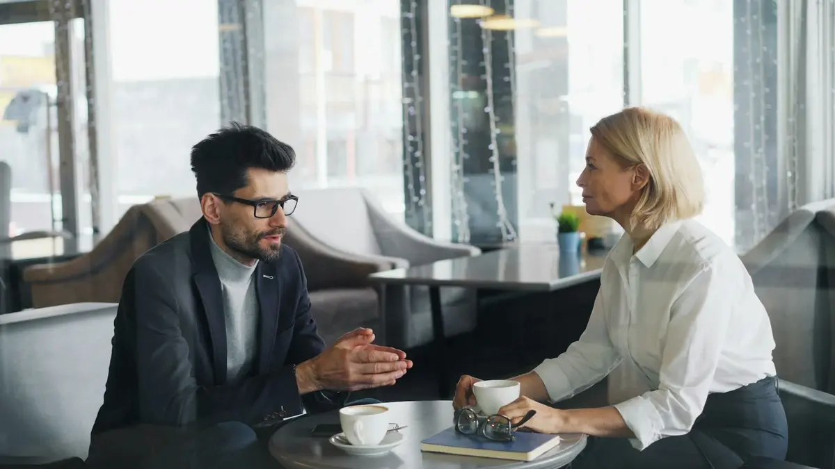 Two adults sitting across a café table in conversation
