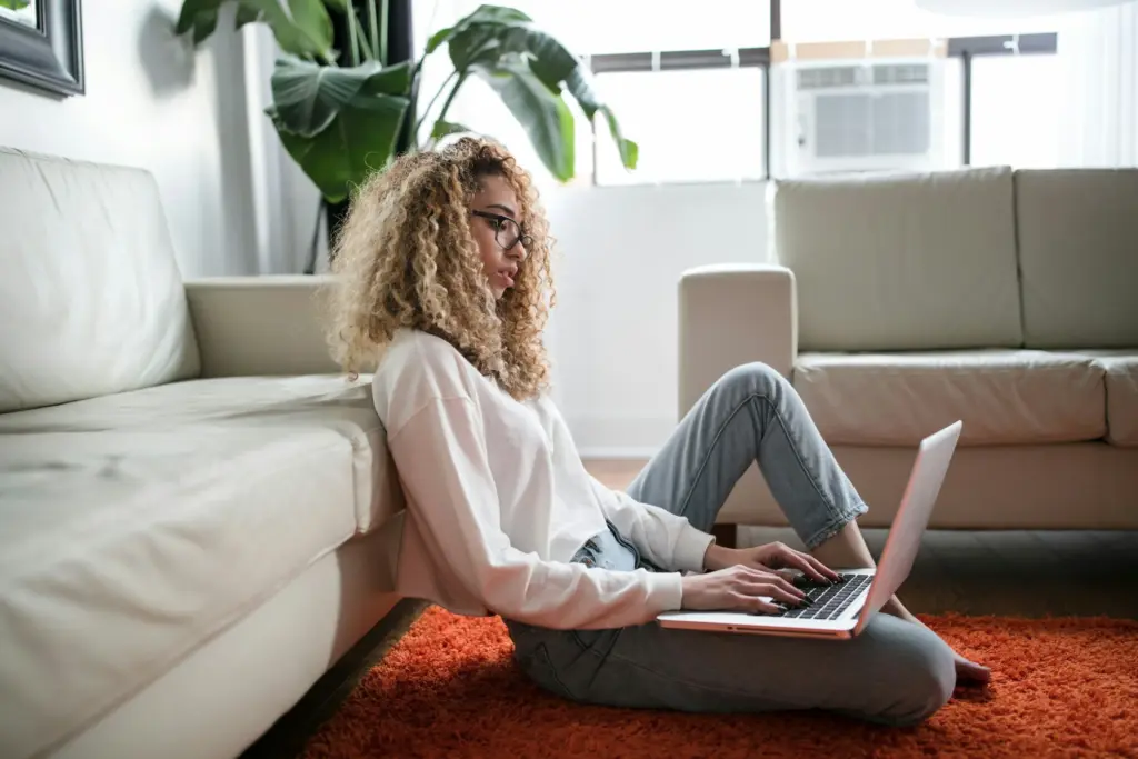 Woman sitting on a couch with a laptop in a bright room