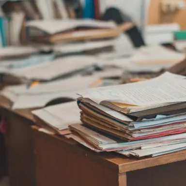 Stacks of papers, folders, and notebooks covering a desk.