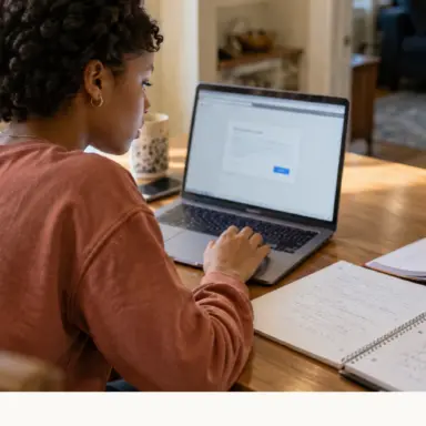 Teen using a laptop to submit schoolwork, with completed notes and a backpack nearby.