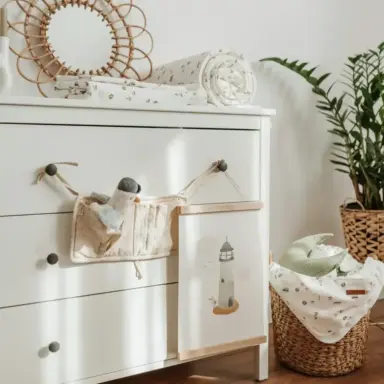 White dresser with a basket and baby items in an organized room