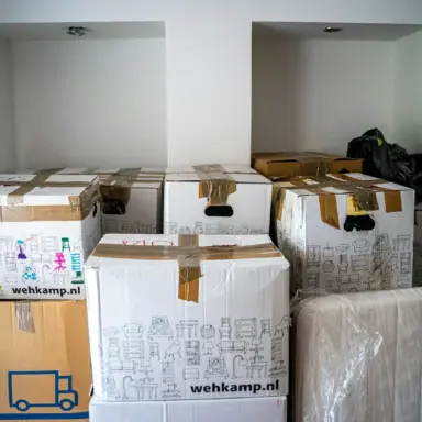 Packed cardboard boxes and wrapped furniture in a room.