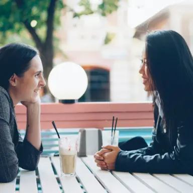 Two women talking across a cafe table
